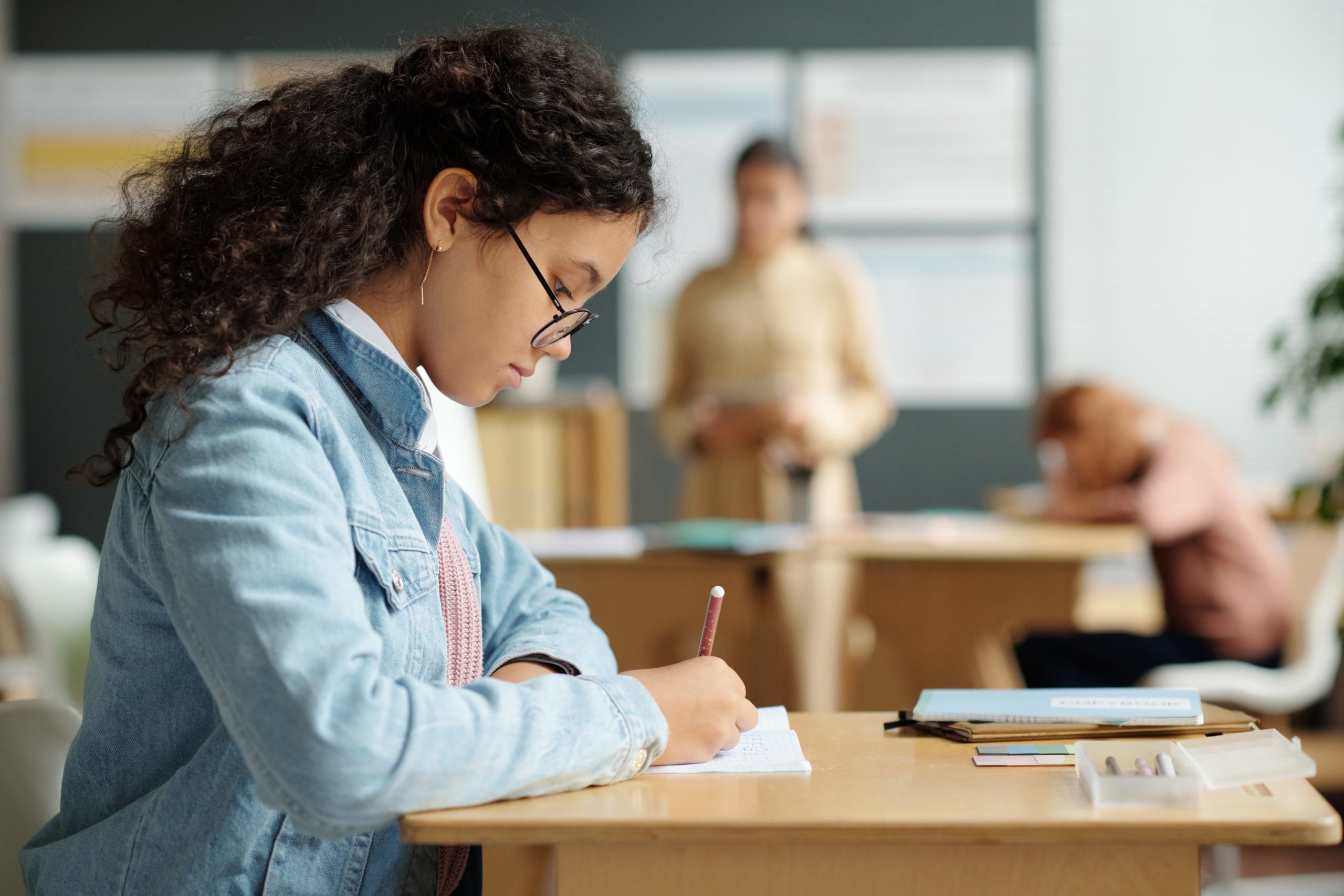 Side,View,Of,Serious,Schoolgirl,In,Eyeglasses,Making,Notes,In